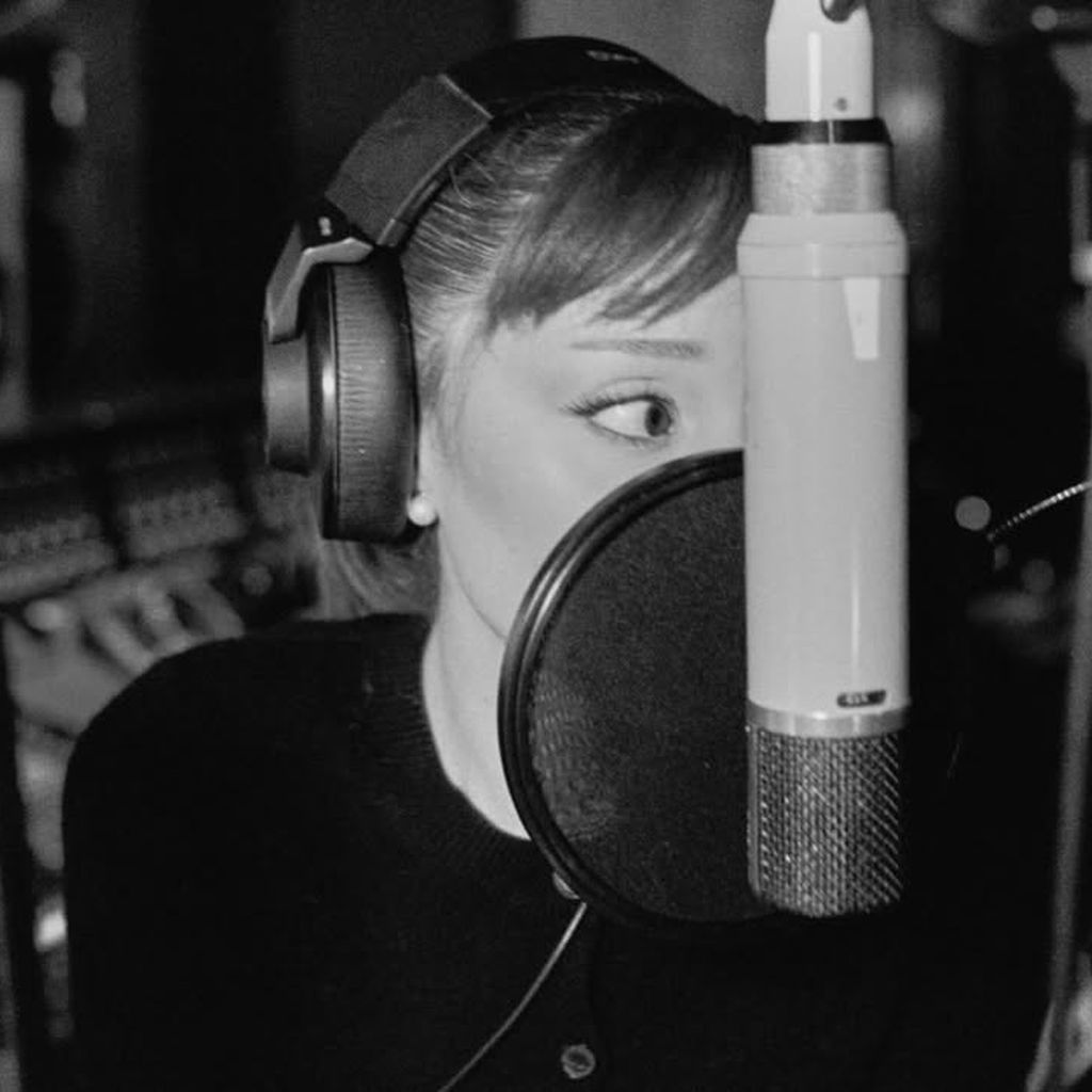 Ariana Grande hinter einem Mikrofon im Studio.