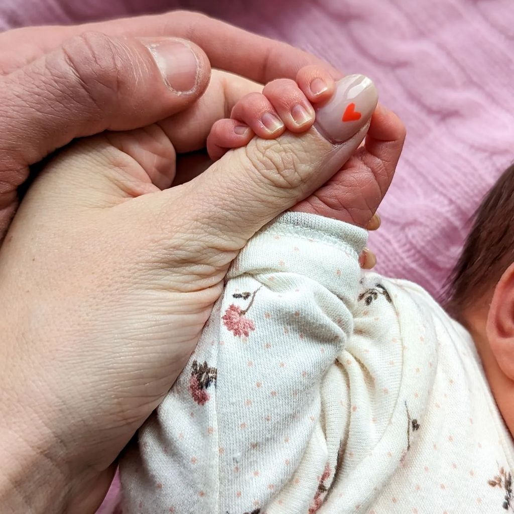 Die Hände von Ashley James, ihrem Partner und ihrem Baby