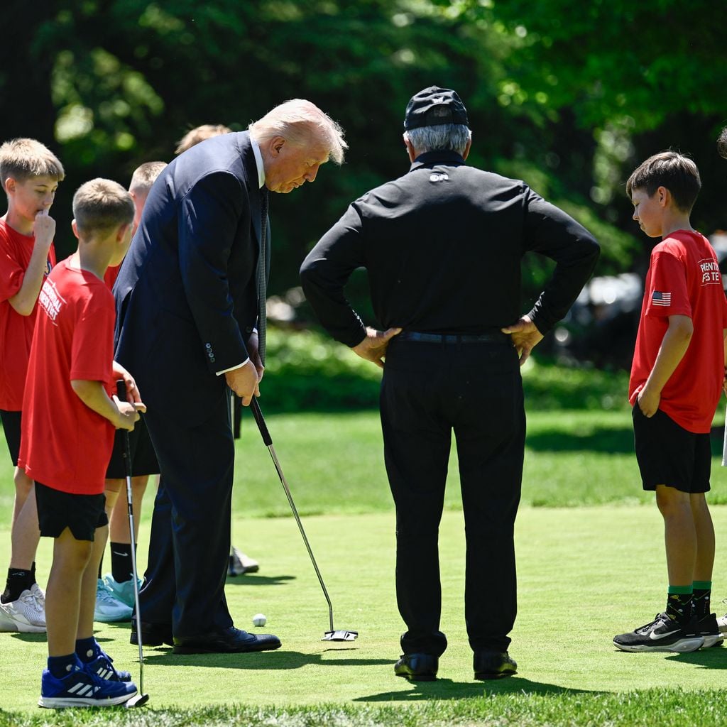 Donald Trump puttet mit Bryson DeChambeau und Gary Player; Schüler verfolgen die Aktion am Weißen Haus