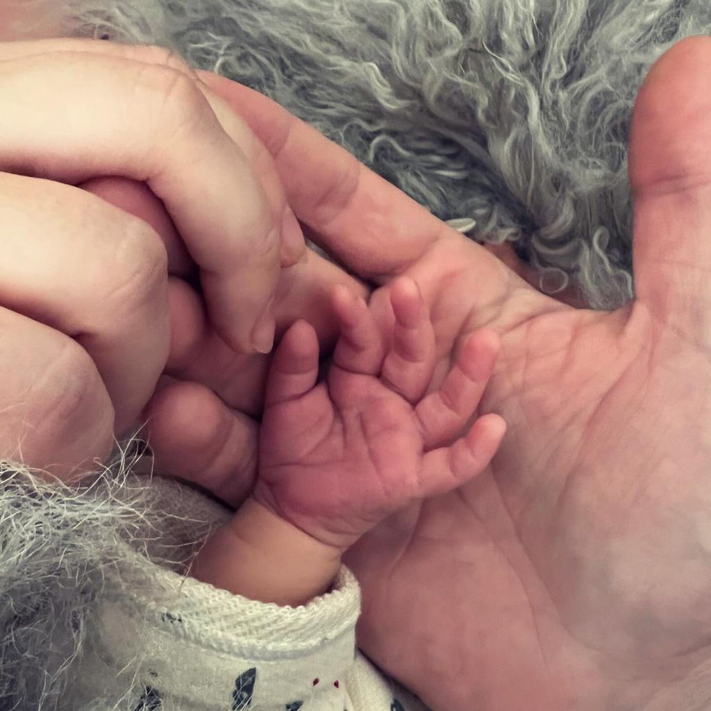 Hände von Nina Gummich, ihrem Partner und ihrem frisch geborenen Baby