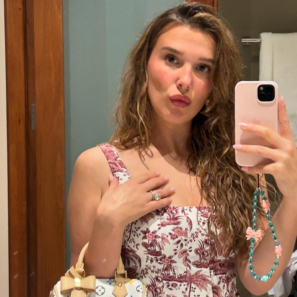 Millie Bobby Brown posiert in floralem Kleid und mit Louis-Vuitton-Tasche