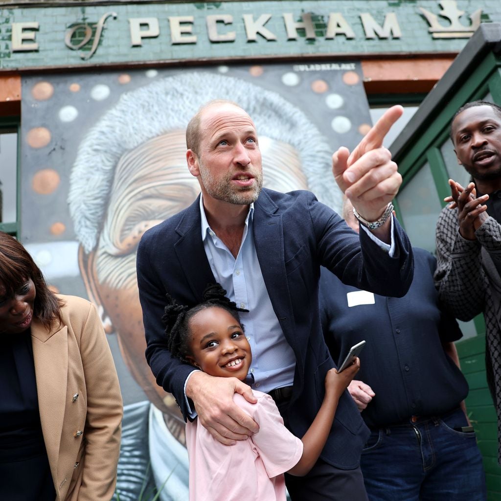 Prinz William umarmt ein Kind vor dem Pub The Prince of Peckham während eines Besuchs in Peckham, London