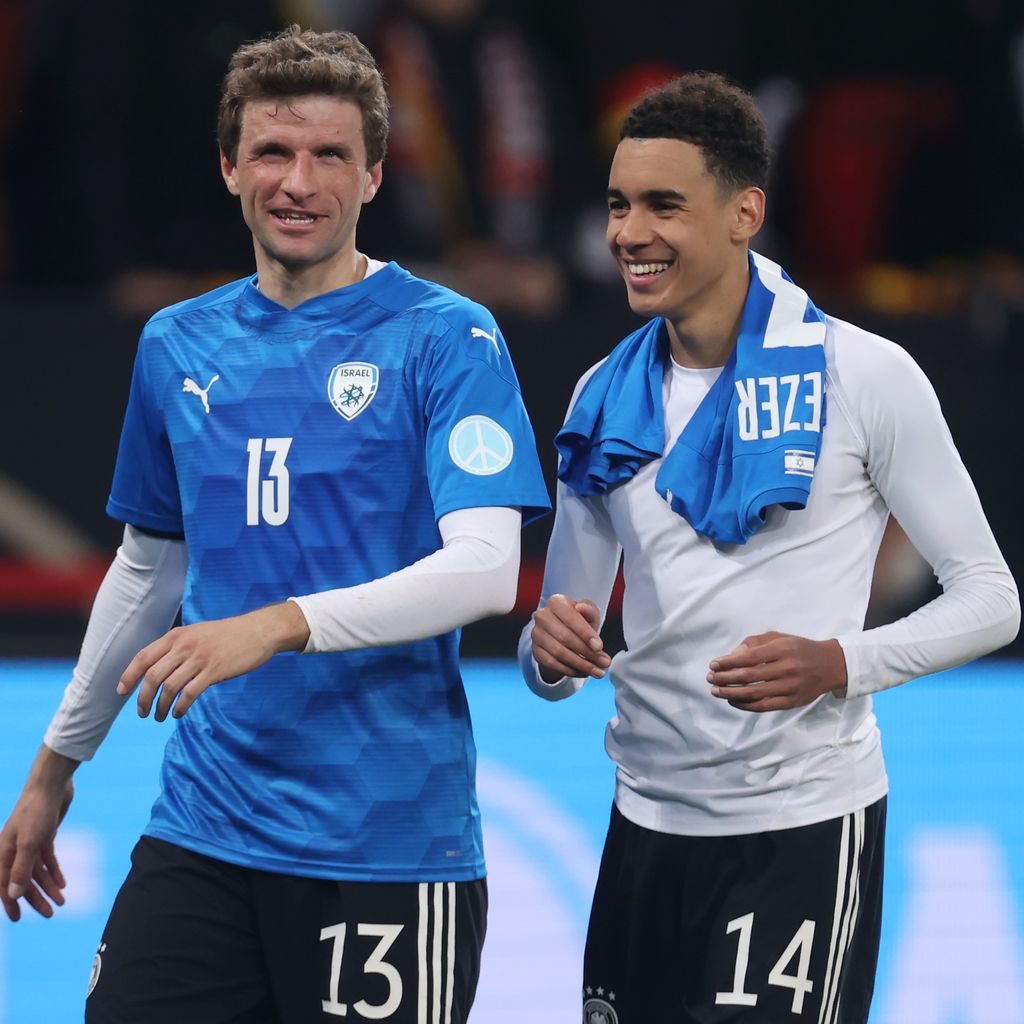 Die Fußballprofis Thomas Müller und Jamal Musiala sind stolz nach einem gewonnenen Spiel.