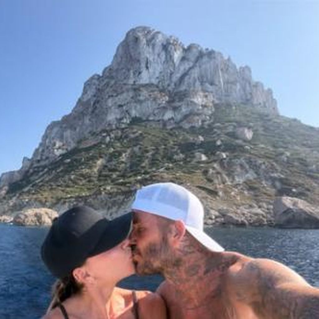 Victora Beckham und David Beckham küssen sich.