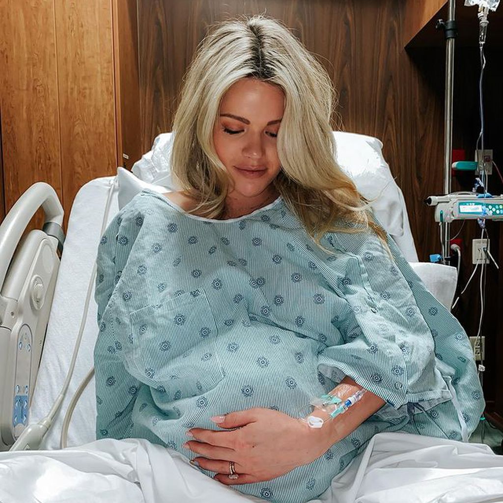 Witney Carson sitzt im Krankenhausbett mit Babybauch