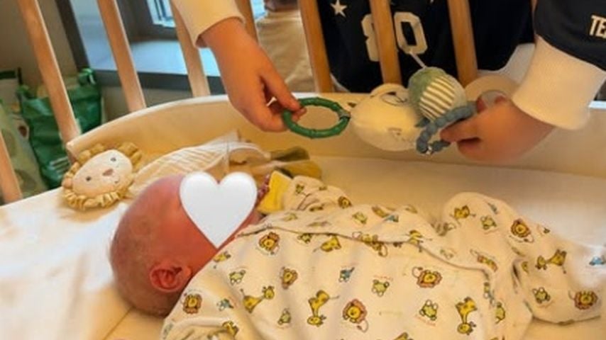 Robert und Alicias Tochter Malia am Babybett von ihrem Brüderchen