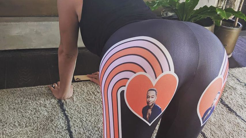 Stolz präsentiert Model Chrissy Teigen eine Leggings, mit dem Gesicht ihres Mannes darauf