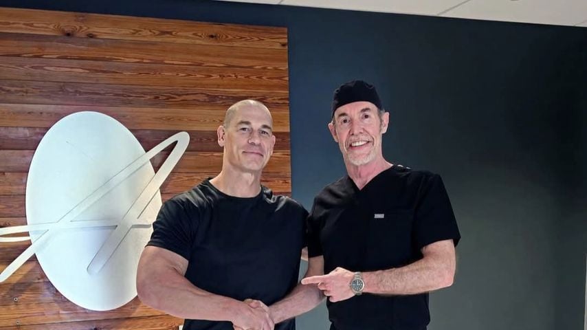 Der ehemalige Wrestler John Cena teilte ein Foto von sich mit glattem Kopf, auf dem er dem Haarchirurgen Dr. Ken Anderson die Hand schüttelt.