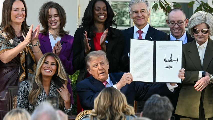 Donald Trump zeigt bei einer Zeremonie im Rosengarten einen unterzeichneten Erlass; Melania Trump applaudiert