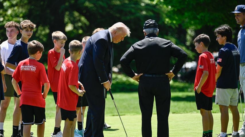 Donald Trump puttet mit Bryson DeChambeau und Gary Player; Schüler verfolgen die Aktion am Weißen Haus