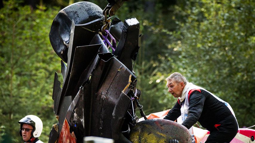 Ein Streckenposten mit dem zertrümmerten Rennwagen von Anthoine Hubert