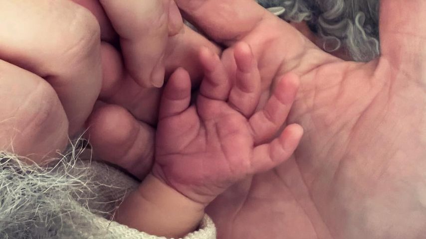 Hände von Nina Gummich, ihrem Partner und ihrem frisch geborenen Baby