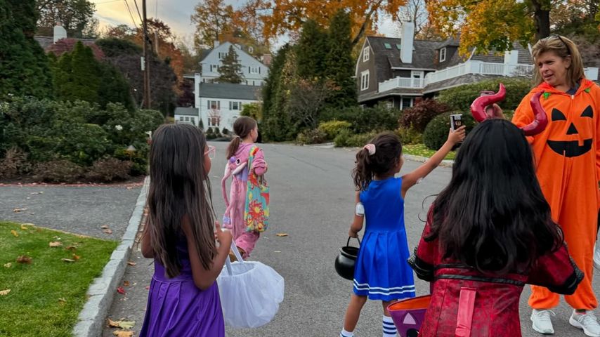 Hoda Kotb in Kürbis-Kostüm mit ihren Töchtern Hope and Haley und weiteren Kindern auf der Straße.