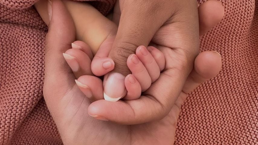 Janique Johnson hält die Hand ihres Babys