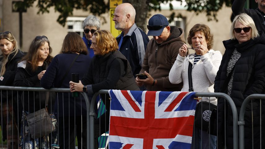 Briten warten an einer Straßensperre auf den Sarg der Queen
