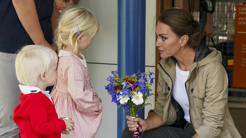Prinzessin Kate nimmt kniend Blumen von Kindern entgegen