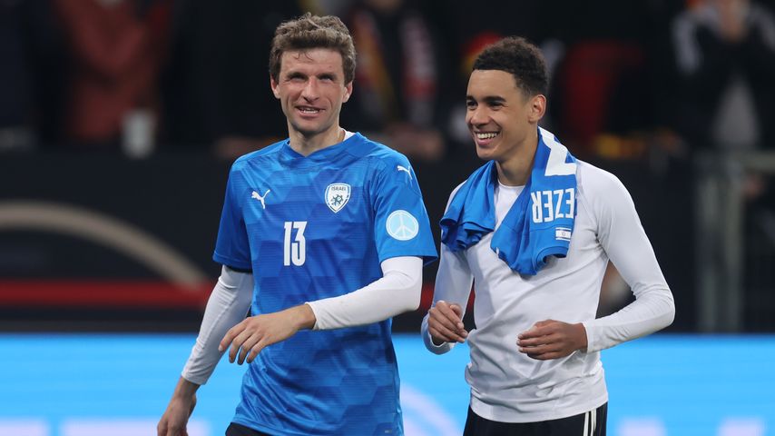 Die Fußballprofis Thomas Müller und Jamal Musiala sind stolz nach einem gewonnenen Spiel.