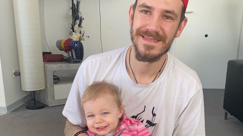 Tim Katzenbauer und Töchterchen Haylie Emilia zeigen einen blauen Strampler