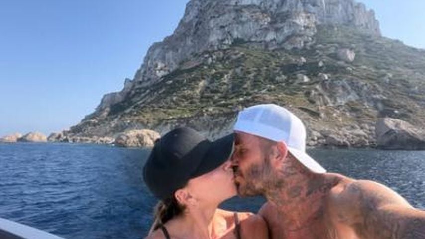 Victora Beckham und David Beckham küssen sich.
