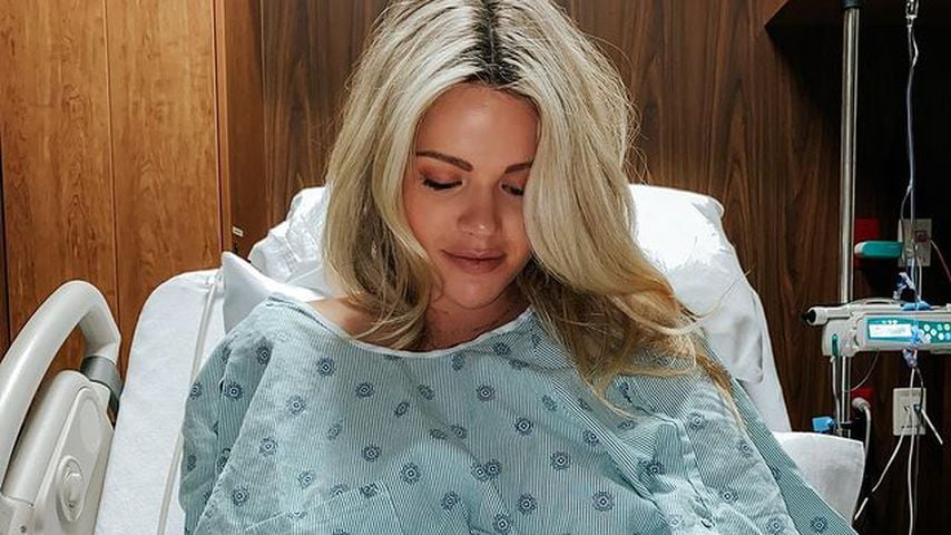 Witney Carson sitzt im Krankenhausbett mit Babybauch
